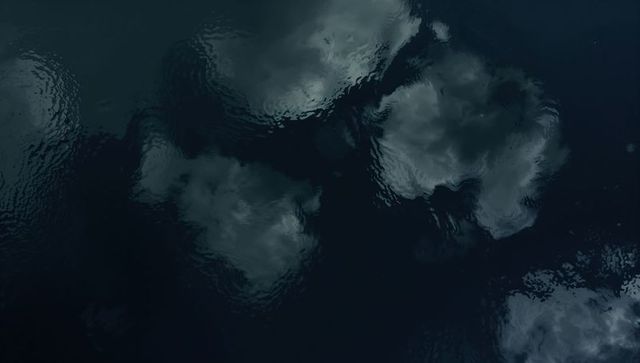 Moody cloud reflections on dark lake surface with gentle painterly ripples