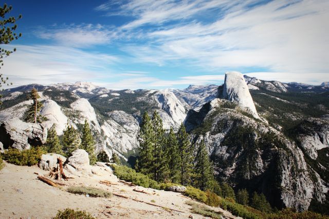 Beautiful vista of Yosemite National Park showcasing the iconic Half Dome, rugged mountains, and clear blue sky. Ideal for promoting travel destinations, outdoor adventures, and nature conservancy.