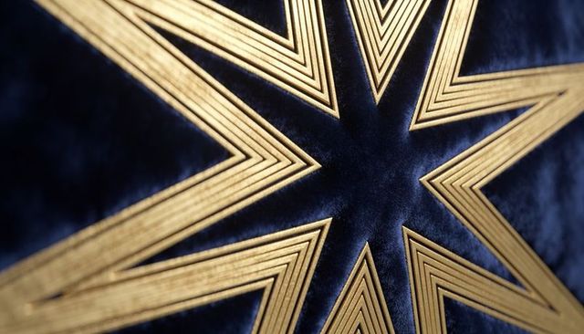 Radiating gold star pattern on navy velvet fabric close-up luxury geometric embossing