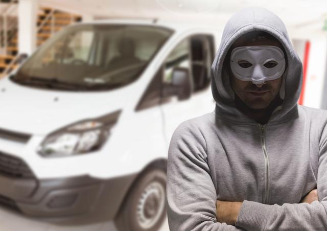 Depicts suspicious person in mask and hoodie standing with folded arms next to a van. Ideal for illustrating crime-related content, security concerns, articles on identity protection, anonymous threats, or security challenges in urban areas.