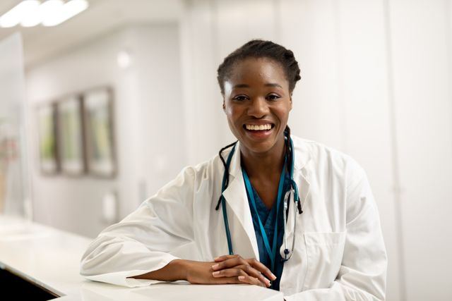 Portrait of smiling african american female doctor leaning on counter in hospital. Medical services, hospital and healthcare concept.