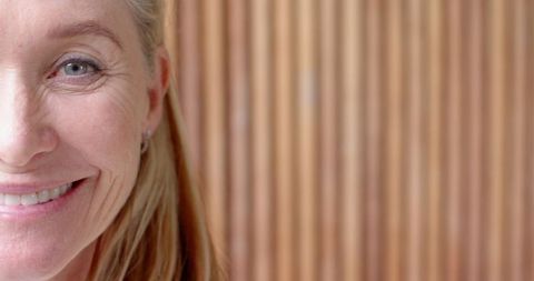 Senior woman in stylish setting smiling at rustic interior wall