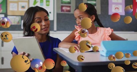 Teacher guiding student with tablet and emoji overlays for interactive classroom learning