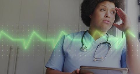 Stressed nurse analyzing ecg data with tablet and stethoscope