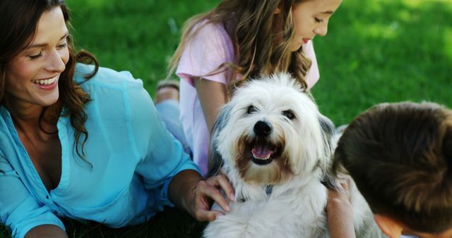 A Caucasian woman and her children enjoy a sunny day outdoors with their fluffy white dog, with copy space. Family moments like these reflect the joy and bonding that pets can bring into people's lives.
