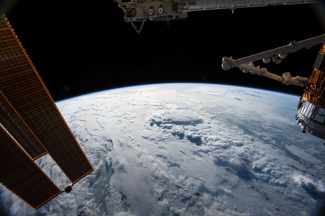 Stunning scene showcasing International Space Station with Earth in background. Visible solar array is essential for power generation. Japanese Exposed Facility shows space experiments. HTV-5 cargo vehicle docked to Harmony module. Ideal for scientific publications, educational resources, space exploration themes.