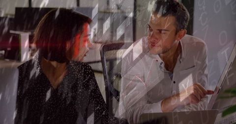 Coworkers discussing data and code on laptop with digital analytics overlay in office