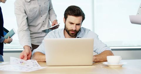 Focused Businessman Working on Laptop with Colleagues Nearby - Download Free Stock Images Pikwizard.com
