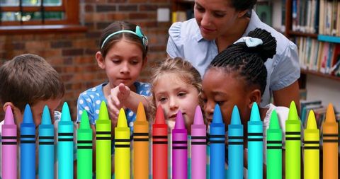 Teacher guiding diverse children in art class with colorful crayons