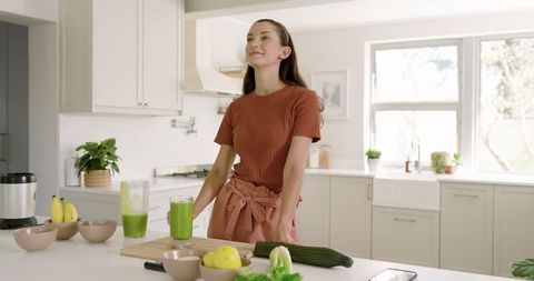 Woman Preparing Fresh Green Smoothie in Modern Kitchen