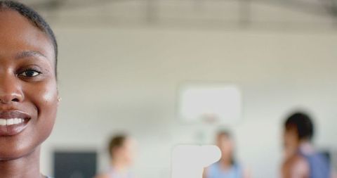 African american woman smiling in gym with basketball team