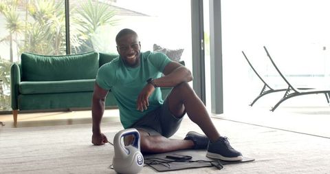 Smiling Man Exercising at Home with Kettlebell and Resistance Bands