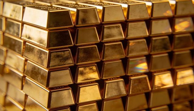 Stacked gold bullion bars reflecting warm light in luxury vault