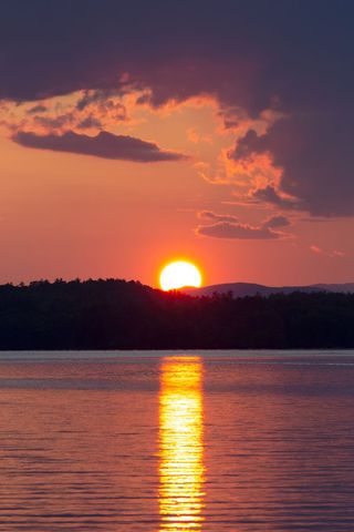 Golden Sunset Over Pine Forest Lake with Reflective Water and Dramatic Clouds