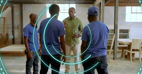 Leading woodworking crew reviewing plans on tablet in spacious carpentry workshop