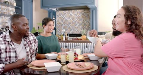 Multicultural friends dining together in modern kitchen