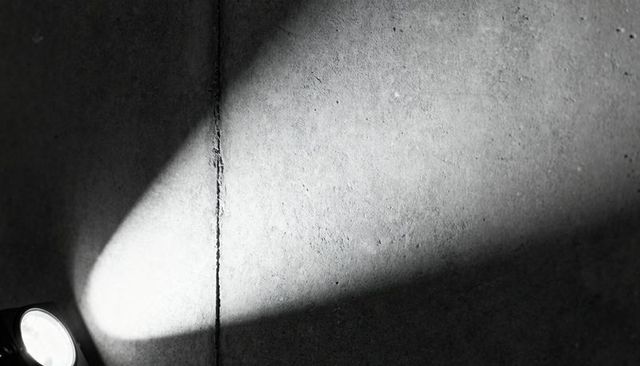 Triangular Spotlight Casting Dramatic Shadow Across Textured Concrete Wall