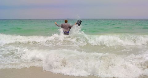 Businessman running with briefcase into sea waves at beach