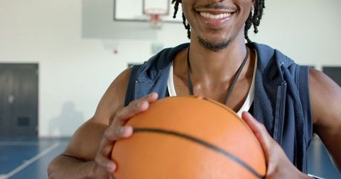 Motivational african american coach holding basketball in gym court
