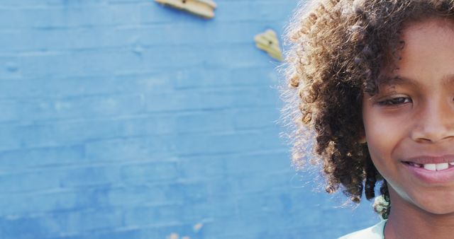 Smiling Child with Curly Hair Against Blue Painted Wall - Download Free Stock Images Pikwizard.com