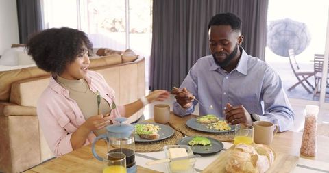 Hispanic woman and African American man enjoying sunlit breakfast with avocado toast