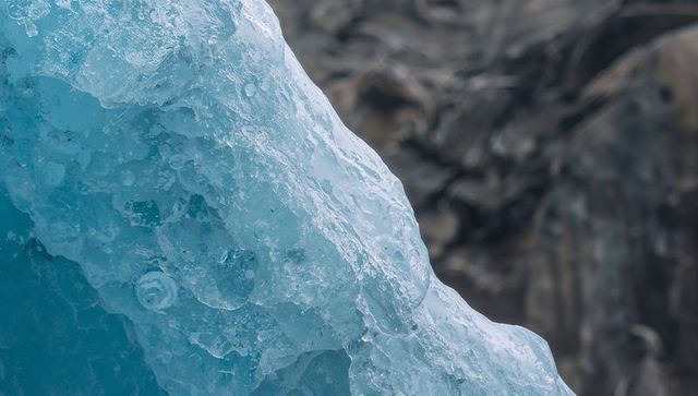Blue glacier ice close-up showing glassy bubbles and crevasses, cool nature background