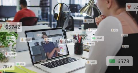 Watching remote presentation on laptop with notification overlays in modern office