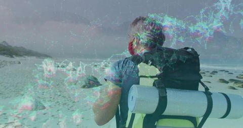 Mature hiker exploring rocky beach with face covering