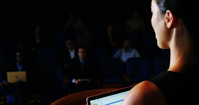 Businesswoman Giving Presentation to Audience in Dark Room - Download Free Stock Images Pikwizard.com