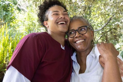 African american senior mother and adult son laughing together in sunny garden embrace