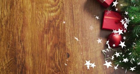 Rustic holiday corner sparkling with red gifts, evergreen sprig and star confetti