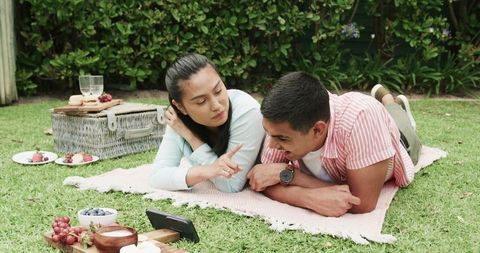 Young Couple Enjoying Outdoor Picnic While Watching Smartphone