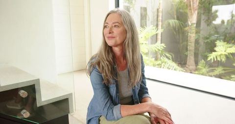 Elegant senior woman relaxing in contemporary home with garden view