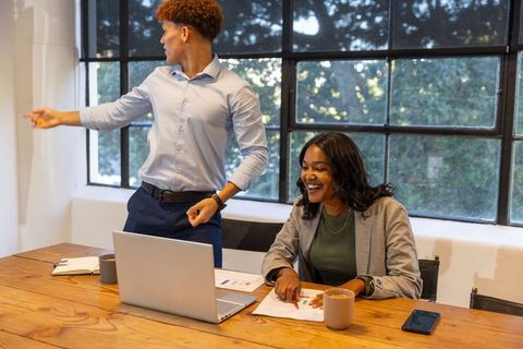African american colleagues collaborating over charts and laptop by window meeting table