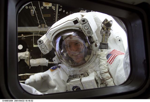 S100-E-5264 (22 April 2001) --- A smiling astronaut Scott E. Parazynski, STS-100 mission specialist, peers into the crew cabin of the Space Shuttle Endeavour during a lengthy spacewalk to perform important work on the International Space Station (ISS). The Pressurized Mating Adapter (PMA-2), which temporarily anchors the orbital outpost to the shuttle, can be seen behind the astronaut.  The picture was recorded with a digital still camera.