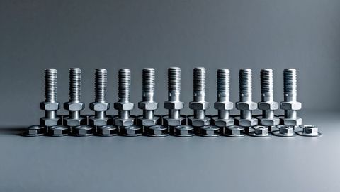 Aligned metallic bolts nuts washers on studio grey tabletop