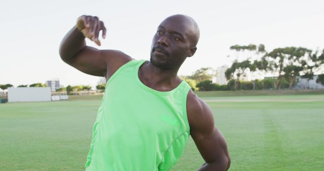 Fit african american man exercising outdoors stretching from the waist. cross training for fitness at a sports field.