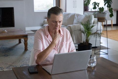 Senior Woman Browsing Laptop in Modern Cozy Living Room
