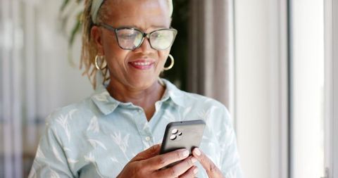 Senior African American Woman Engaged with Smartphone Indoors