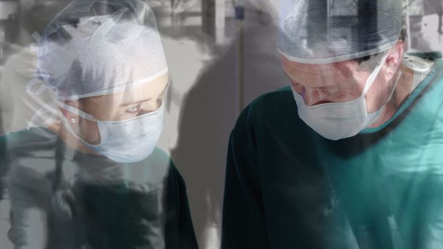 Two surgeons in surgical attire focus on performing a complex medical task, overlaid with a timelapse visual of people walking in a city. This imagery captures the high-stakes environment of healthcare surgeries amidst the bustling rush of urban life. Useful for depicting concepts in healthcare, stress environments, multitasking, or illustrating the integration of modern medicine with fast-paced city dynamics. Ideal for educational content, healthcare articles, and urban life discussions.