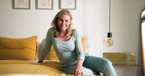 Elderly Woman Enjoying Relaxation in Bright Cozy Bedroom