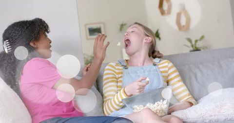 Teen Girls Laughing While Enjoying Popcorn Together