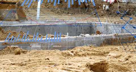 Augmented reality surveying revealing concrete footings in sandy excavation for site planning