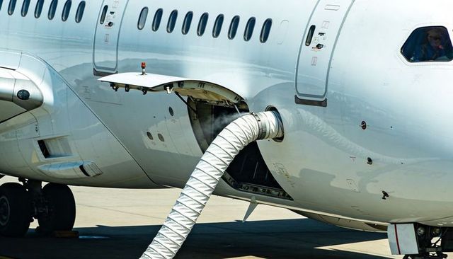 Ground servicing duct connecting aircraft service panel on airport ramp with pilot visible