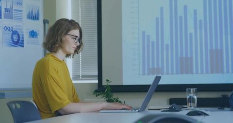 Businesswoman Analyzing Data on Laptop in Modern Conference Room