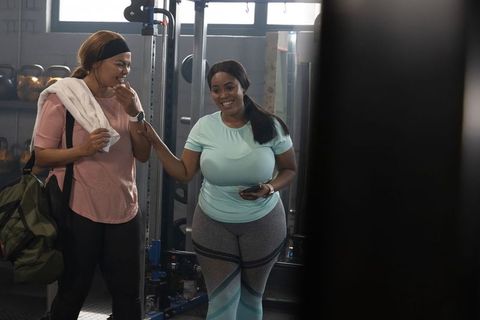 African american women laughing and preparing for workout in modern gym environment