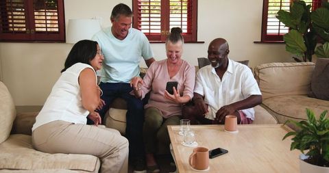 Diverse Friends Sharing Fun Moments on Smartphone at Home