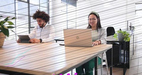 Middle eastern man and chinese woman collaborating at modern open-plan office desk