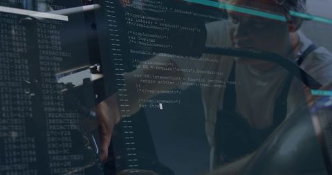 Coder reviewing code on multiple monitors with glass reflection in dim workspace