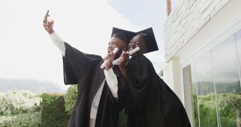 Graduates celebrating success outdoors with diplomas